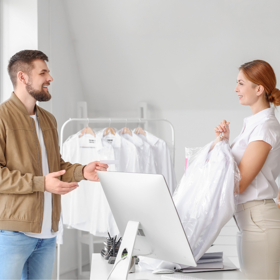 smiling customer picking up garments from dry cleaner
